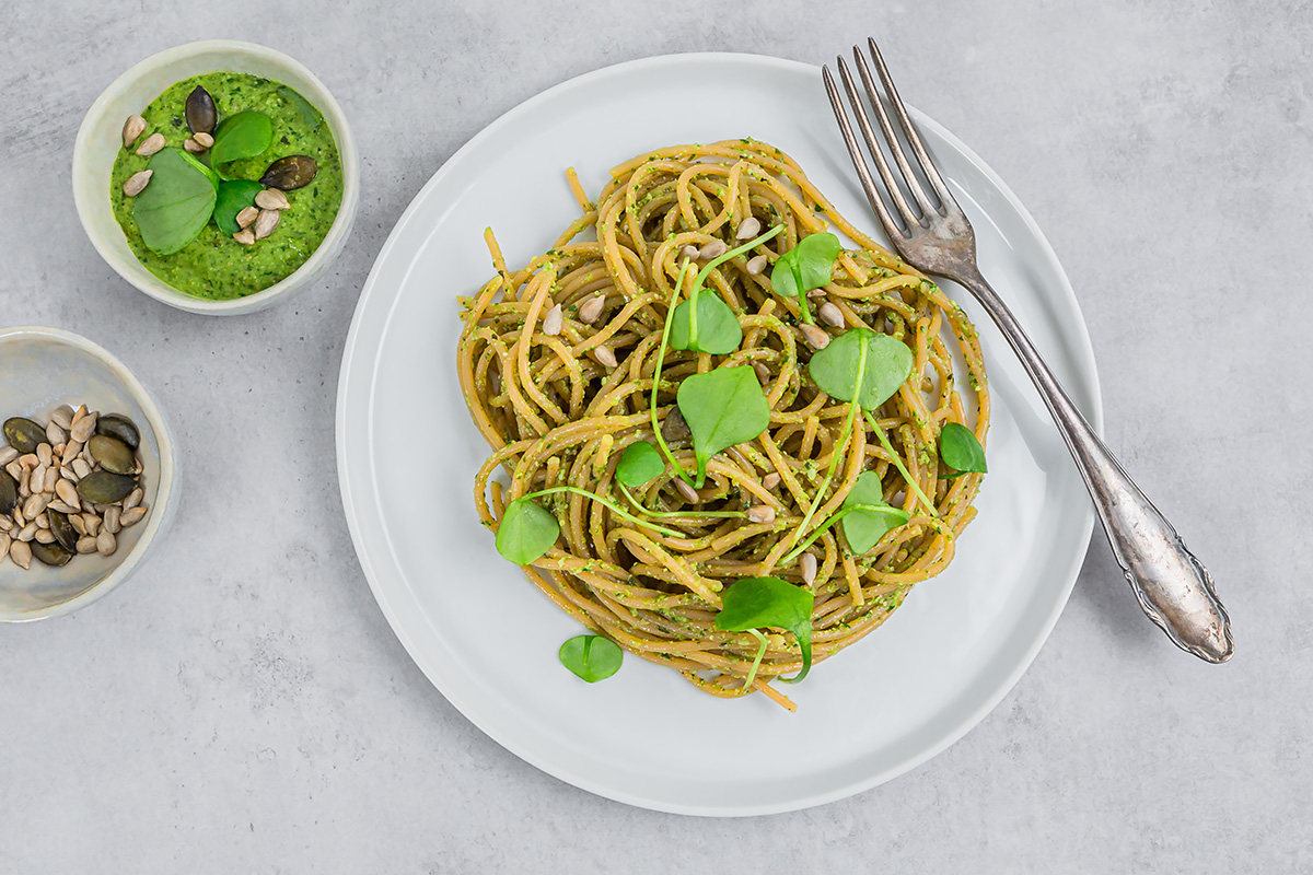 Teller mit Spaghetti aus roten Linsen mit Portulak-Pesto steht zum Essen bereit.