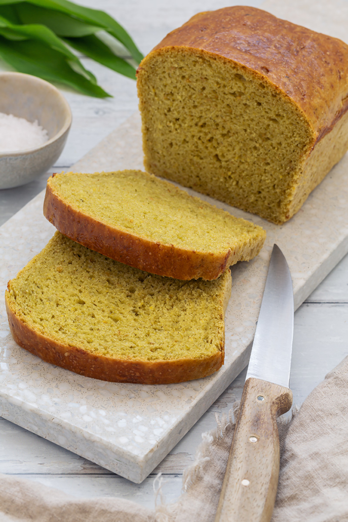 Angeschnittener Brioche-Laib auf einem Schneidebrett, daneben liegt ein Messer.